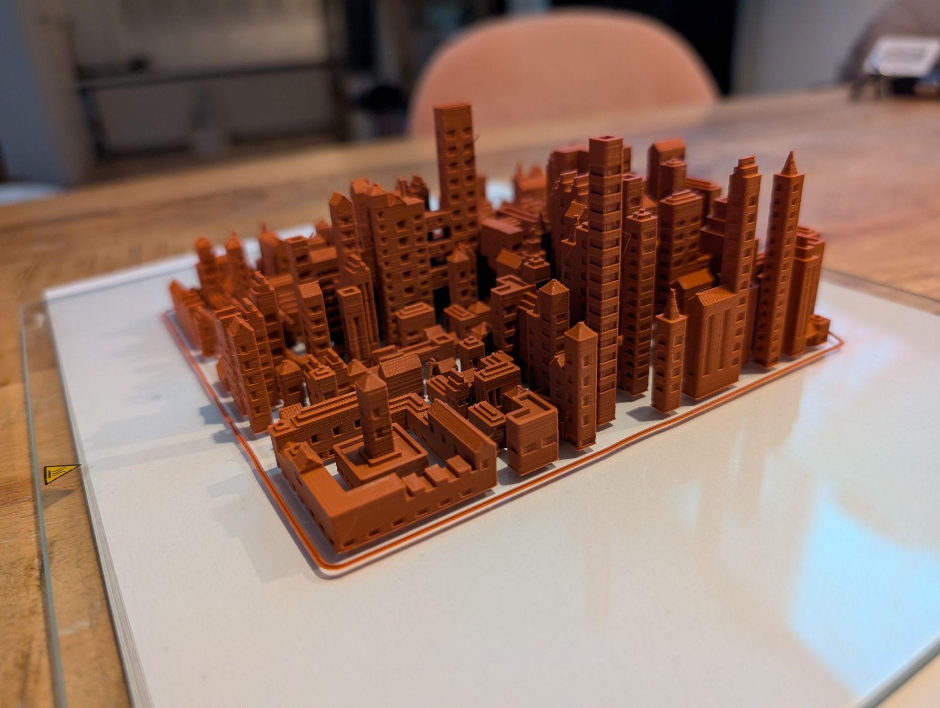A printed Urban QR city in orange filament: towers, roofs and arches on a white plate